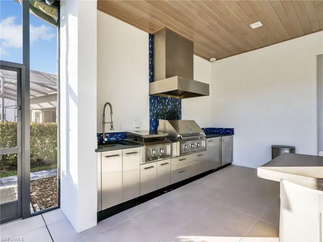 Custom Outdoor Kitchen With Hestin Stainless Steel Appliances Including Grill, Separate Cooktop, Beverage Fridge, Hood, and Sink