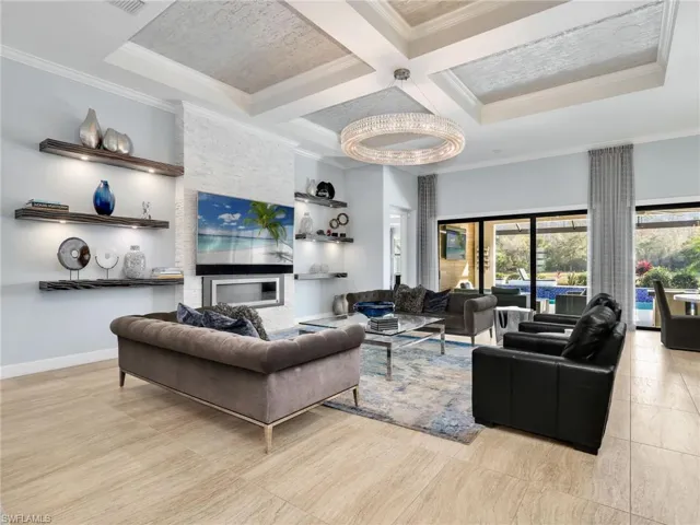 Great Room Living Area with Stone Feature Wall With Fireplace, Custom Shelving With Integrated Lighting, WHOLE-HOME SONOS AUDIO With In-Ceiling Speakers & Soundbars, and Wi-Fi Extenders, Restoration Hardware Chandelier, Custom Draperies, and Sliders To The Lanai/Pool Area