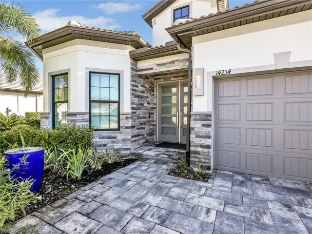 Front Outdoor Entry with Water Feature, Custom Door, Gray Paver Driveway, and Custom Coach Light