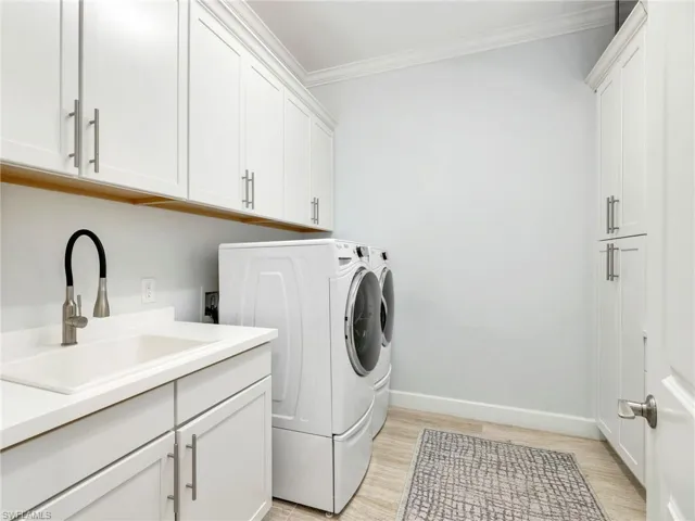 Large Laundry Room with Custom Cabinetry, Utility Sink, and Washer & Dryer with Pedestals
