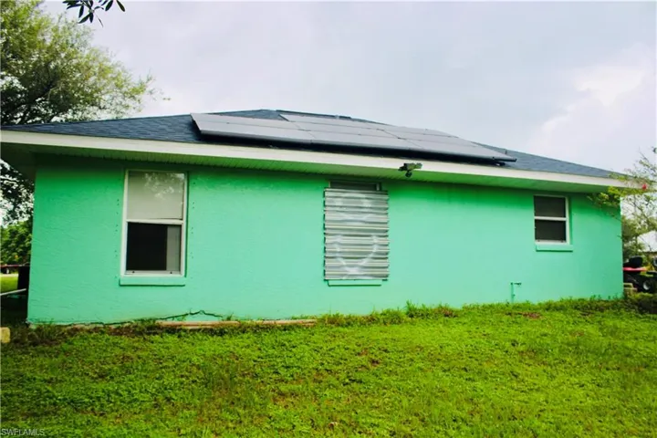 View of side of home with a yard and solar panels