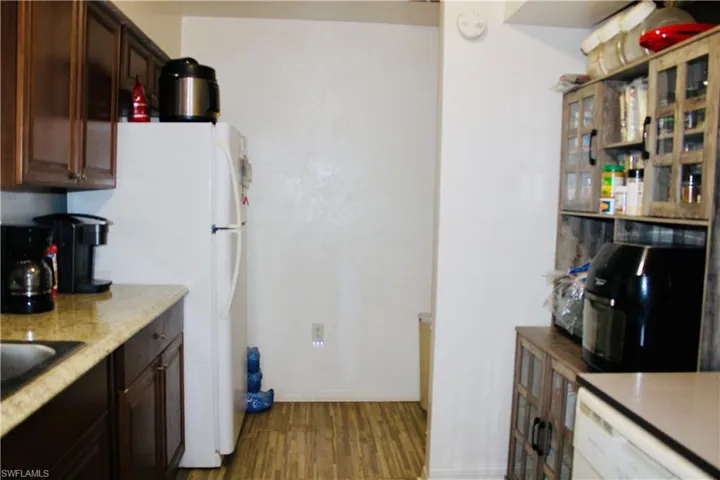 Kitchen featuring dark brown cabinets, white fridge, and hardwood / wood-style flooring