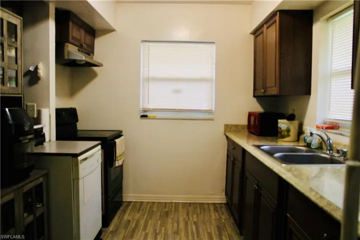Kitchen featuring black appliances, sink, wood-type flooring, and dark brown cabinets