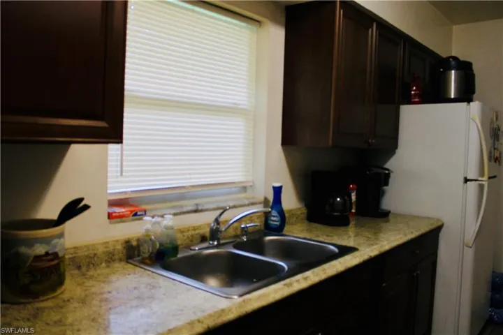Kitchen featuring white fridge, dark brown cabinetry, and sink