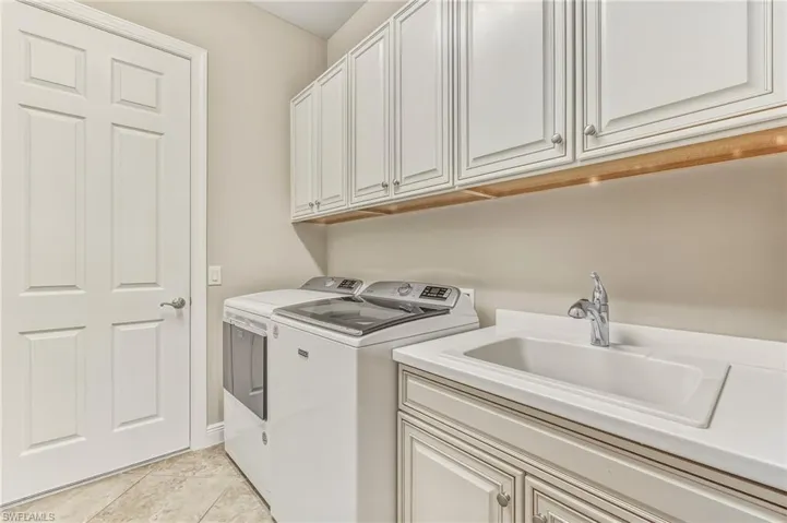 Washroom featuring light tile patterned floors, washer and dryer, and cabinet space