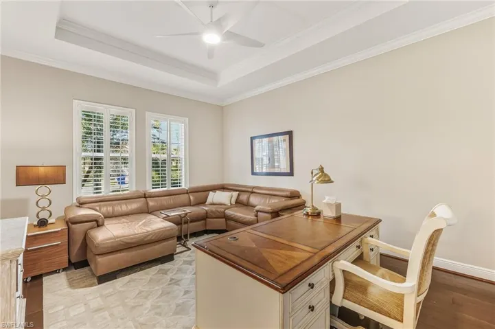 Office area with a tray ceiling, ornamental molding, light wood-type flooring, and a ceiling fan