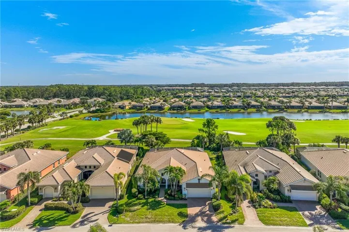 Aerial view of residential area featuring a golf course and a nearby body of water