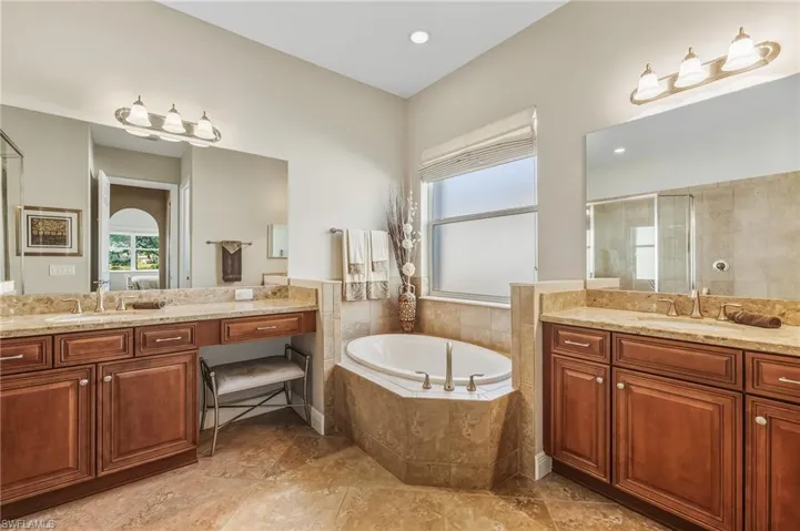 Full bath featuring a garden tub, a stall shower, two vanities, recessed lighting, and light tile patterned floors