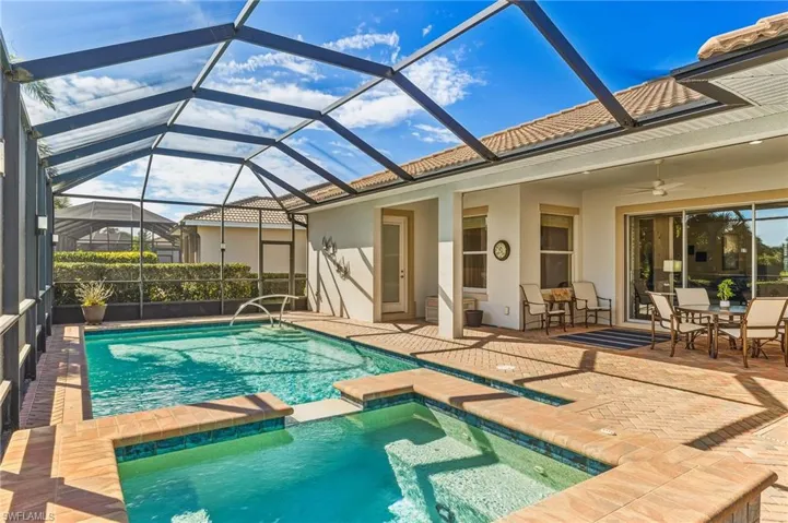 View of swimming pool featuring a patio, a sunroom, a pool with connected hot tub, and a lanai