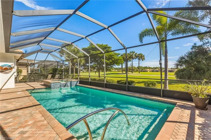 View of swimming pool featuring a sunroom, a pool with connected hot tub, glass enclosure, a patio area, and golf course view