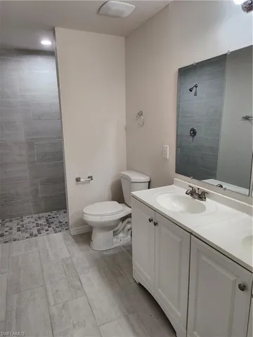 Bathroom with toilet, vanity, and a tile shower
