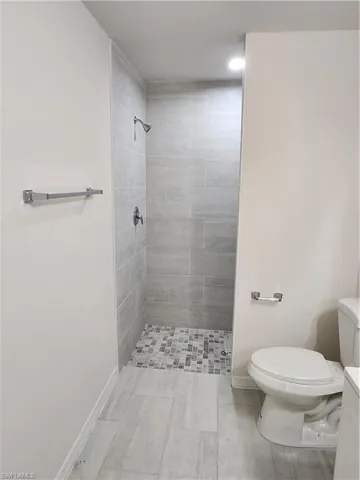 Bathroom with toilet, vanity, and a tile shower