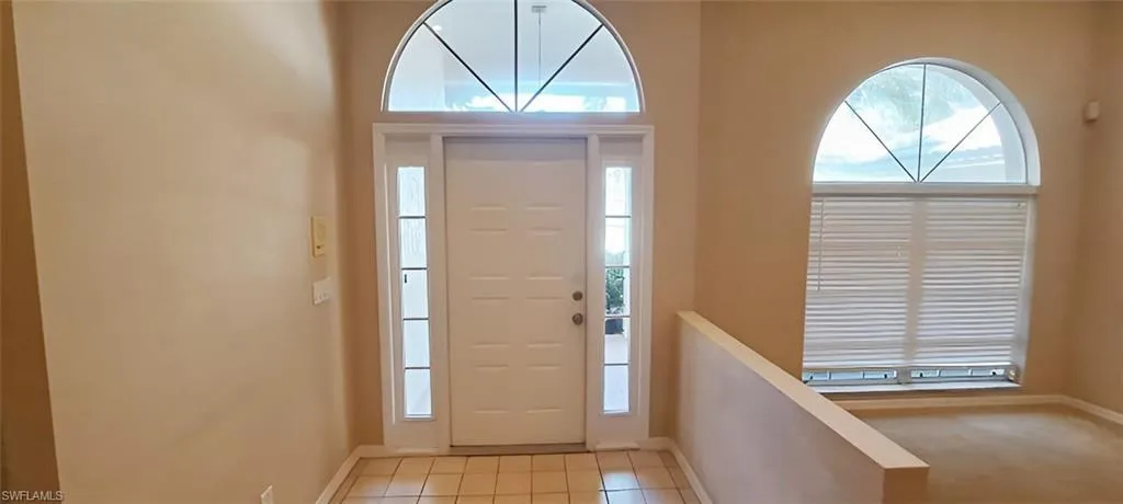 Foyer entrance with light carpet and a healthy amount of sunlight