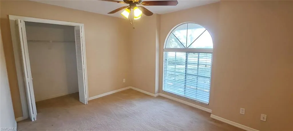 Unfurnished bedroom featuring light carpet, ceiling fan, and a closet