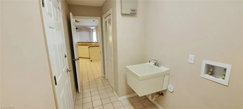 Laundry room with washer hookup, light tile patterned floors, and sink