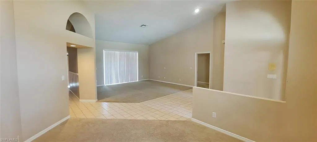Carpeted spare room featuring high vaulted ceiling