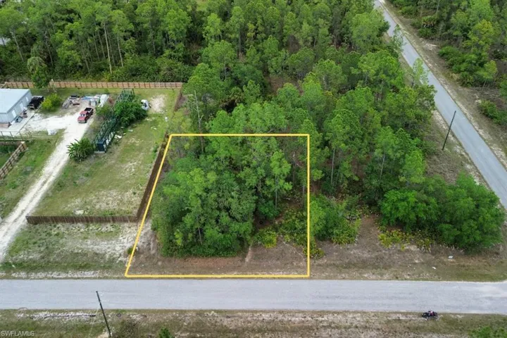 Vacant land parcel featuring mature trees and established frontage on a paved road