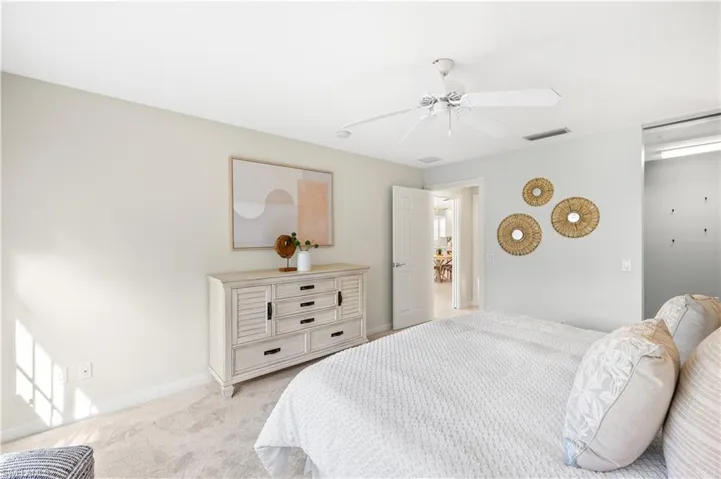 Bedroom with baseboards, ceiling fan, visible vents, and light carpet