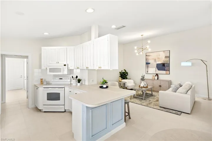 Kitchen with light countertops, white appliances, visible vents, a peninsula, and a notable chandelier