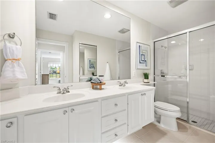 Full bathroom with a stall shower, visible vents, tile patterned flooring, and a sink