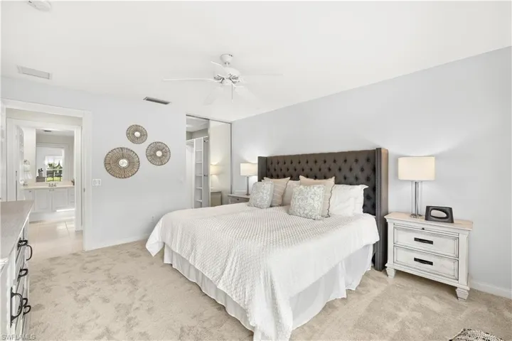 Bedroom with a closet, visible vents, baseboards, ceiling fan, and light carpet