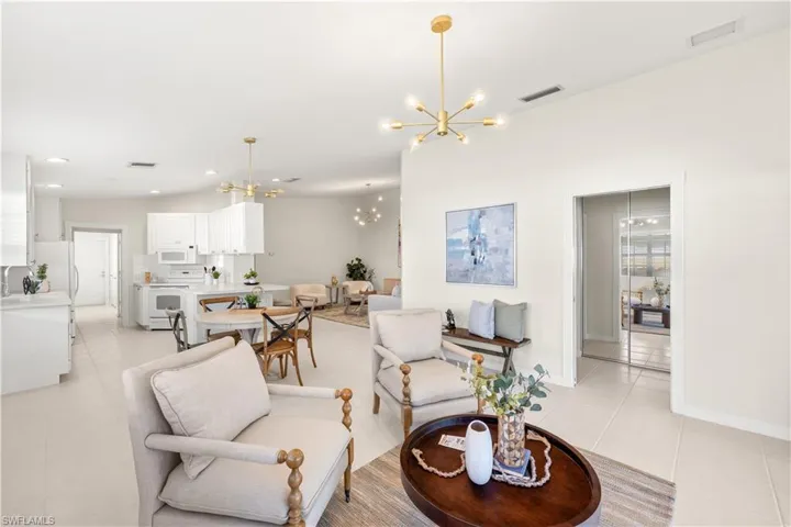 Living room with light tile patterned flooring, visible vents, baseboards, recessed lighting, and an inviting chandelier