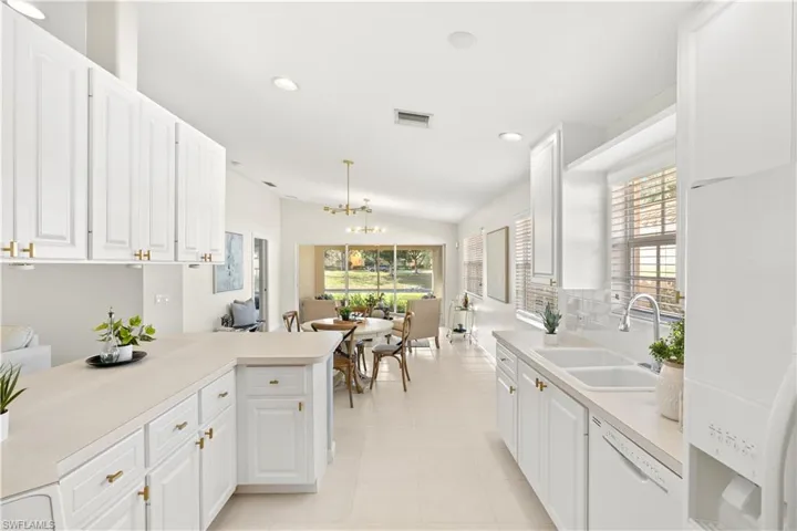 Kitchen featuring light countertops, visible vents, white appliances, a sink, and a notable chandelier
