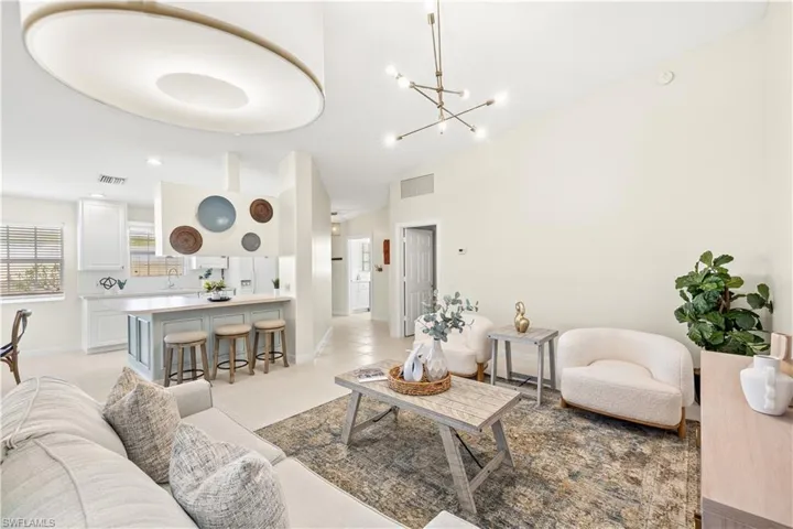 Living room featuring light tile patterned floors, baseboards, a chandelier, and visible vents