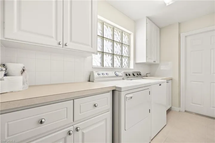 Laundry area featuring light tile patterned flooring, cabinet space, and separate washer and dryer