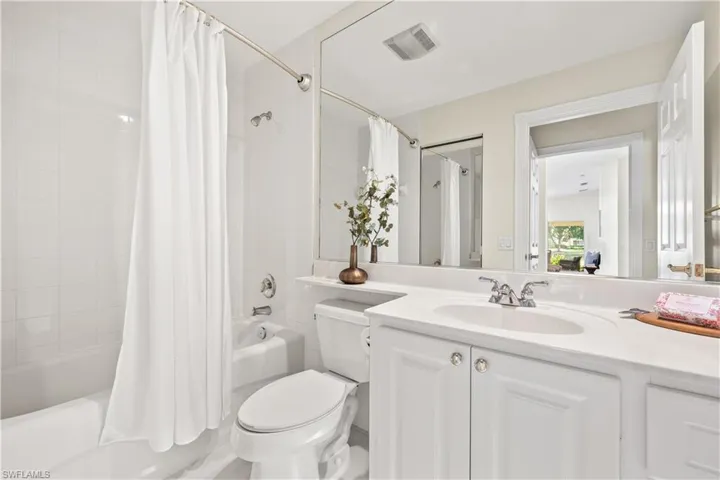 Full bath with visible vents, shower / bath combo with shower curtain, toilet, and vanity