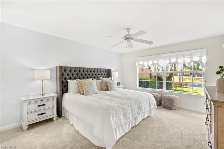 Bedroom featuring light carpet, baseboards, and ceiling fan