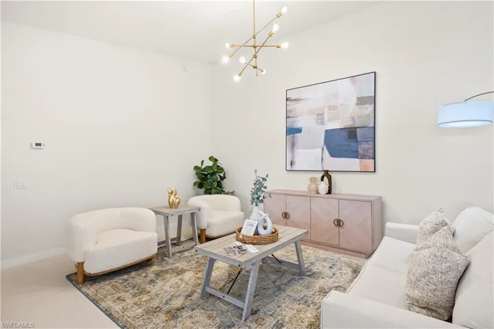 Living area with baseboards, light tile patterned floors, and a chandelier