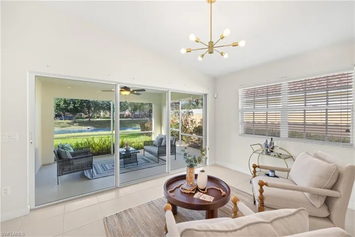 Living area with tile patterned floors, ceiling fan with notable chandelier, lofted ceiling, and baseboards