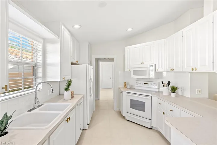 Kitchen featuring white cabinetry, a sink, and white appliances