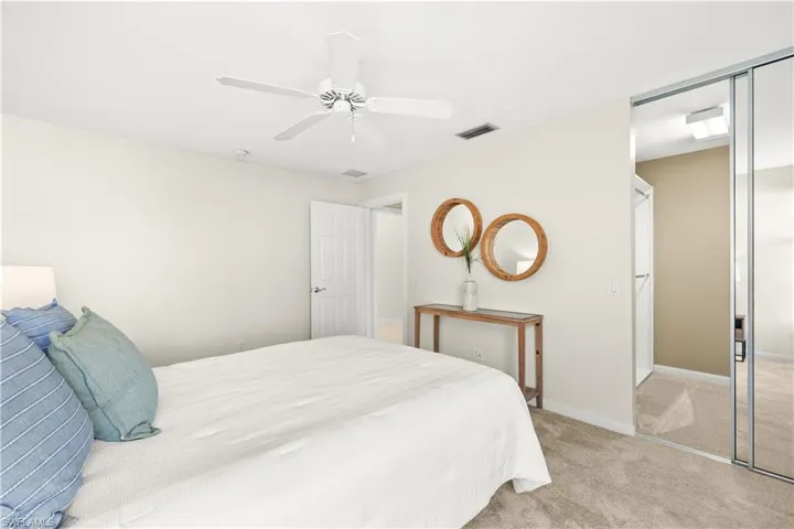 Bedroom featuring a closet, visible vents, baseboards, ceiling fan, and light carpet