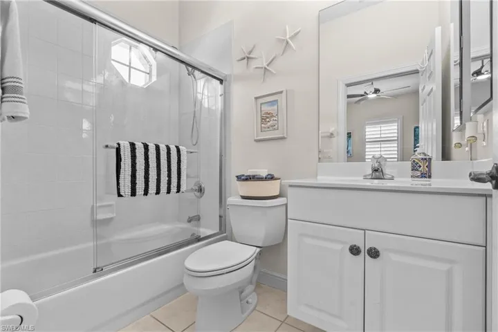 Bathroom featuring a tub/shower combination with sliding glass doors, a single vanity with a white countertop, and integrated cabinetry
