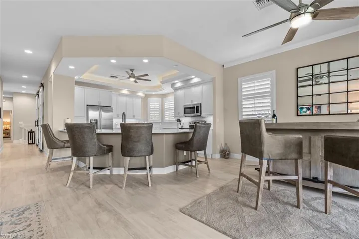 Open-concept kitchen featuring recessed lighting, a tray ceiling, and light wood-finish flooring