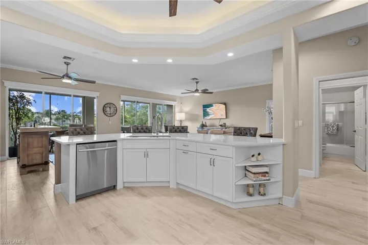 Kitchen island with white cabinetry, stainless steel dishwasher, and a light-toned countertop