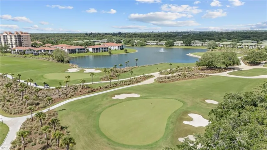 Golf course setting featuring manicured greens and sand traps, lake with fountain, and mature palm trees