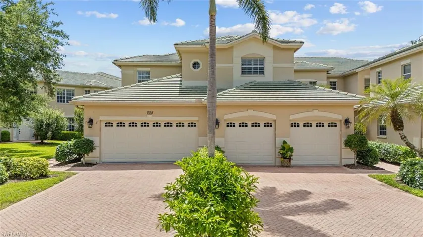 Two-story stucco exterior with a tile roof, dual two-car garages, and paver driveways