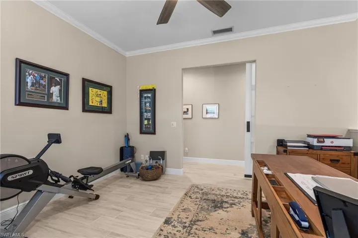 Recessed ceiling with crown molding, ceiling fan, and wood-finish flooring