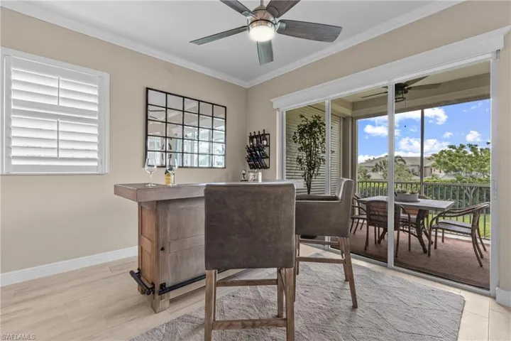 Sliding glass door leading to a screened lanai with an outdoor dining area, wood-finish flooring, and crown molding