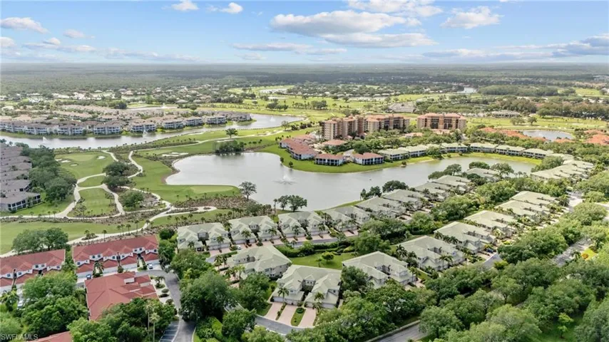 Aerial landscape featuring multiple residential properties, a golf course, and a lake with a water feature