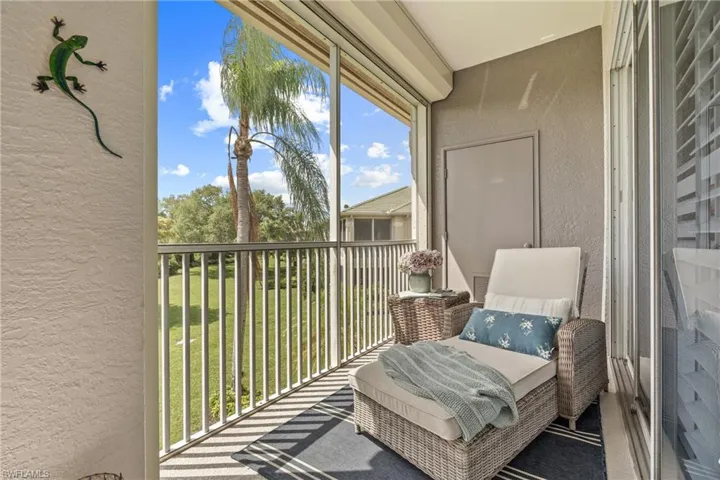 Screened balcony featuring a white railing, textured exterior wall, and roll-down sunshade