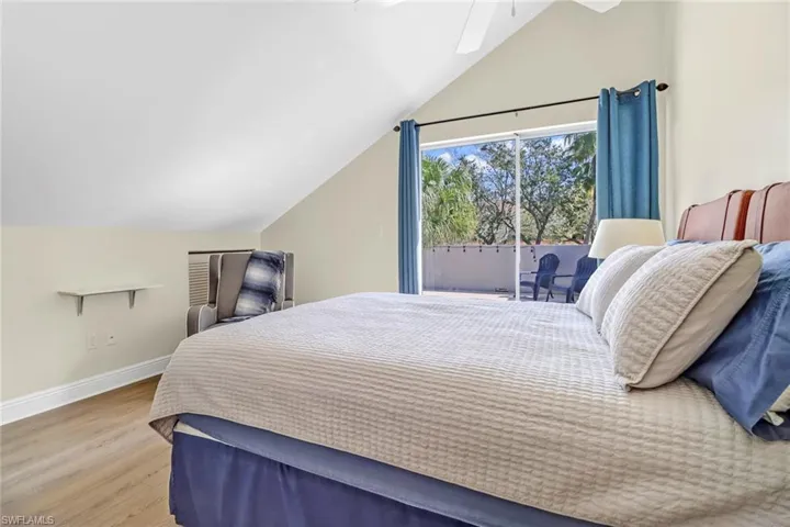 Bedroom with vaulted ceiling, wood finished floors, access to exterior, and ceiling fan
