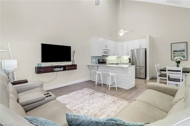 Living area with light wood-style flooring, a high ceiling, and ceiling fan