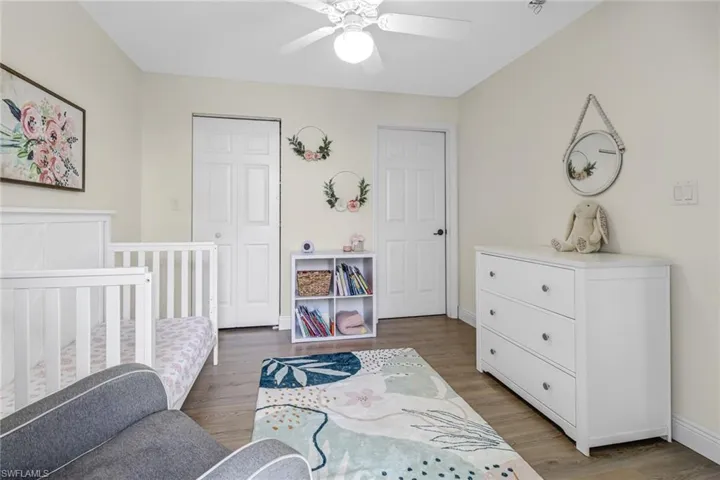 Bedroom with a nursery area, light wood finished floors, a closet, and ceiling fan