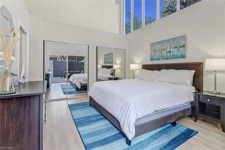 Bedroom featuring two closets, a high ceiling, and light wood-style flooring