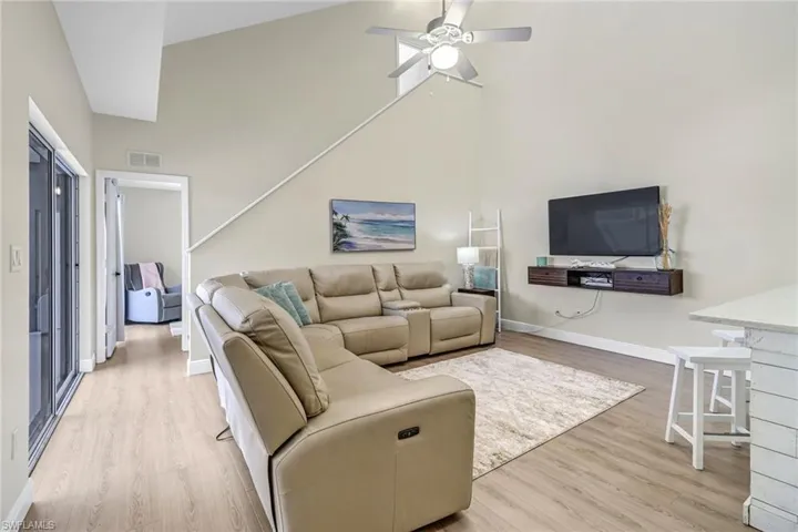 Living area featuring a towering ceiling, light wood finished floors, and a ceiling fan