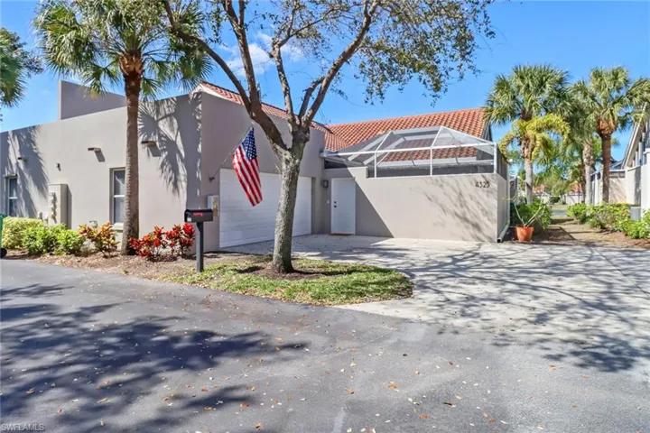View of front of house featuring driveway, glass enclosure, stucco siding, a garage, and a tiled roof